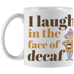 Front view of the white coffee mug displaying the complete 'I laugh in the face of decaf' phrase and the expressive cartoon woman, showcasing the mug's design and handle.