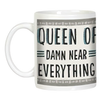 White ceramic mug with handle, clearly displaying the sassy phrase 'QUEEN OF DAMN NEAR EVERYTHING' in bold black text, framed by a decorative gray border. A funny and empowering gift for women.