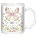 White ceramic coffee mug with watercolor butterfly and floral design. Features inspirational quote 'He RESTORES my SOUL Psalm 23:3' in elegant typography, perfect for spiritual comfort.