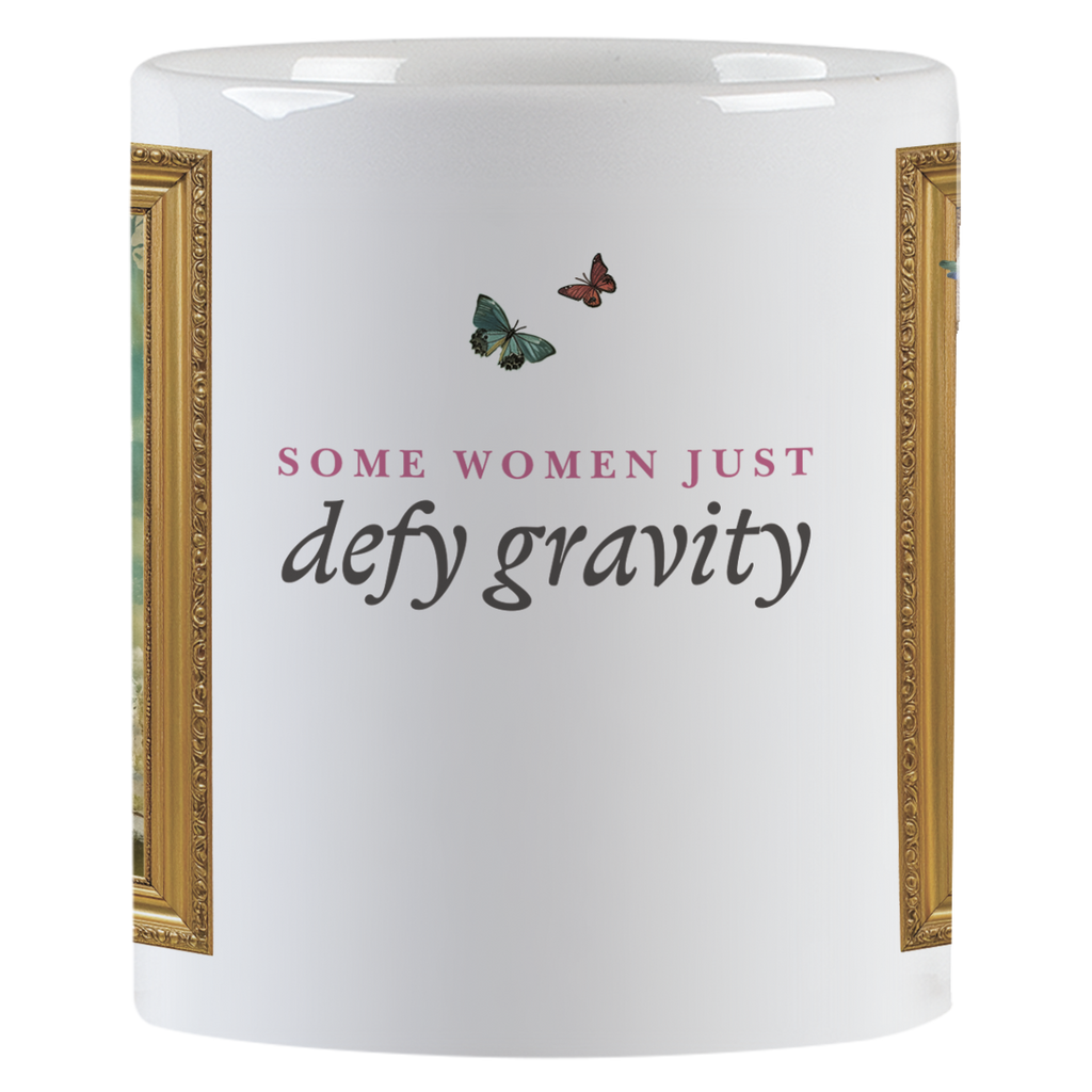 Side view of the white ceramic mug with the empowering text "SOME WOMEN JUST defy gravity" in elegant typography, accompanied by two small butterflies.