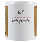 Side view of the white ceramic mug with the empowering text "SOME WOMEN JUST defy gravity" in elegant typography, accompanied by two small butterflies.