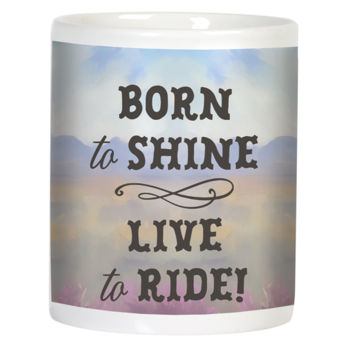 Back view of a white ceramic mug displaying the inspirational text "BORN to SHINE LIVE to RIDE!" in dark brown script over a soft watercolor background with distant mountains and a serene sunset sky.