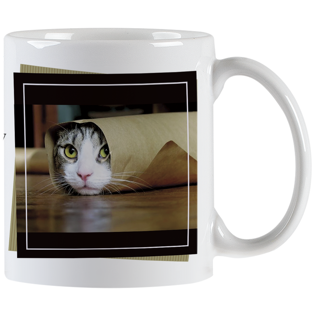 Close-up of a white ceramic mug featuring a tabby cat peeking out from a rolled-up brown paper bag with bright green eyes, framed by a black border.