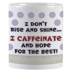 Close-up view of the white ceramic coffee mug displaying the humorous text 'I don't rise and shine... I CAFFEINATE AND HOPE FOR THE BEST!' with purple polka dots.