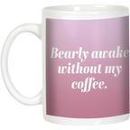 White ceramic coffee mug with 'Bearly awake without my coffee' text in elegant white font on a soft pink background, ideal funny coffee lover gift.