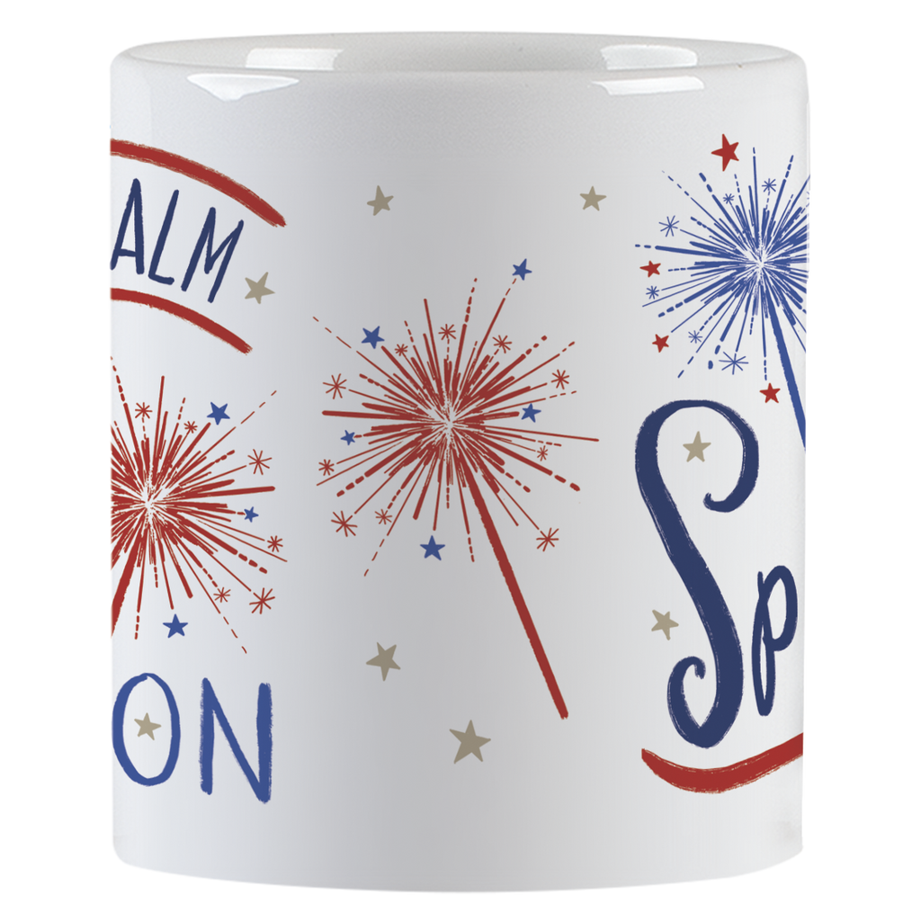 Close-up view of a white ceramic mug, showing red and blue sparkler graphics and parts of the 'Keep Calm and Sparkle ON' text.