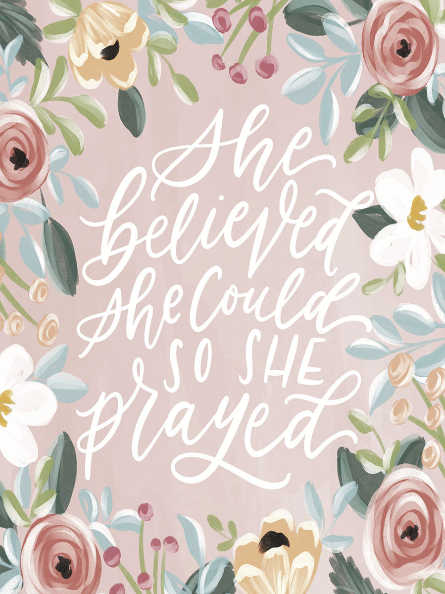Front view of a religious floral greeting card for women, featuring the quote 'She believed she could so she prayed' in elegant white script, framed by delicate watercolor pink, yellow, and white roses with green foliage on a soft pink background.