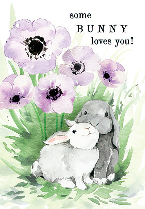 Watercolor greeting card front featuring two cute bunnies, a white and a gray, cuddling amidst delicate purple anemone flowers and vibrant green grass, with the playful text 'some BUNNY loves you!'. Perfect for a child's spring celebration or special occasion.