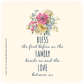 Coaster with a watercolor floral bouquet featuring pink, yellow, and blue flowers, above the blessing text 'BLESS the food before us the FAMILY beside us and the LOVE between us' on a light cream background.