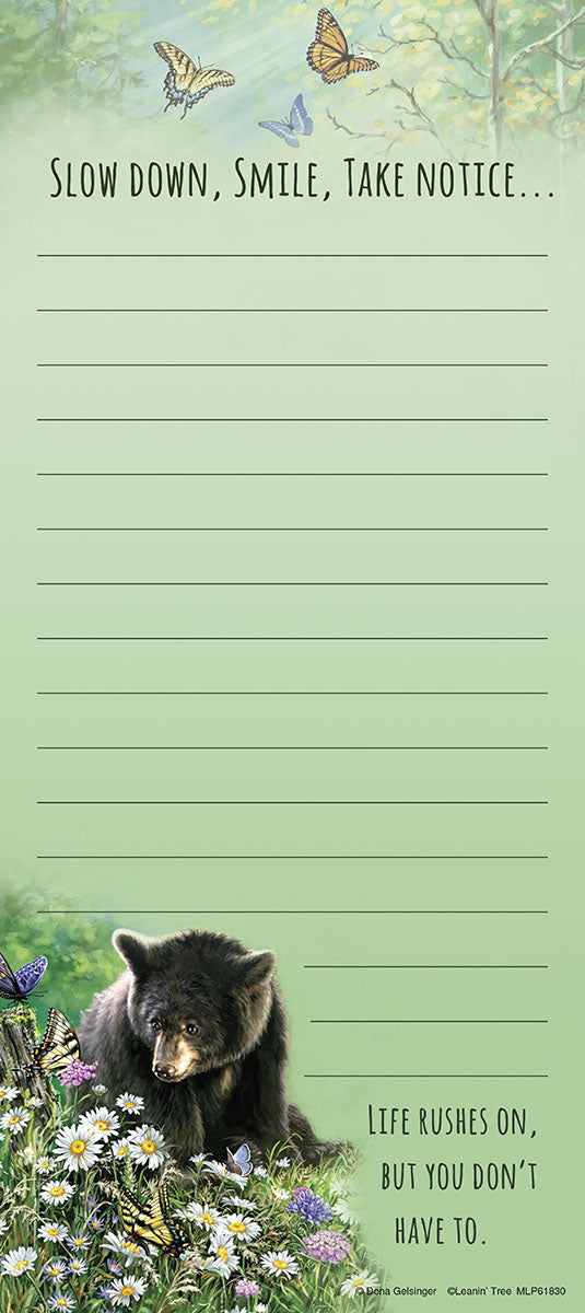 Magnetic listpad with a calming nature scene, featuring three colorful butterflies flying above trees. The top has the text 'Slow down, smile, take notice...'. The bottom shows a peaceful black bear cub sitting among white daisies and purple wildflowers, with a yellow butterfly nearby. The bottom text reads 'Life rushes on, but you don't have to.'. The notepad has ample blank lines for writing. Ideal for daily reminders and thoughtful organization.