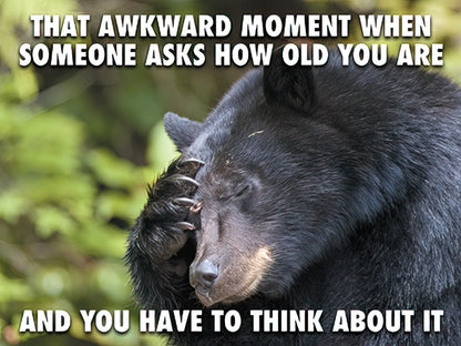 Front of a relatable birthday card featuring a black bear covering its face, with text about 'THAT AWKWARD MOMENT WHEN SOMEONE ASKS HOW OLD YOU ARE'.