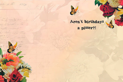 Inside of a humorous birthday card with the text 'Aren't birthdays a pisser?!' against a floral background.
