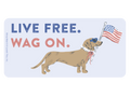 Light blue rectangular vinyl sticker featuring a cartoon dachshund dog in blue heart sunglasses, a white collar, and pink bow, proudly holding a pole with the American flag. Bold text reads 'LIVE FREE. WAG ON.' in blue and coral. Perfect patriotic dog decal for laptops, cars, and water bottles.
