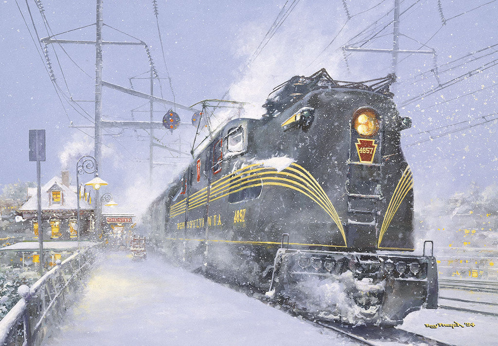 Front of a vintage holiday greeting card. Features a detailed painting of a powerful black Pennsylvania Railroad GG1 locomotive, number 4857, traveling through a heavy snowstorm. The train's headlamp shines brightly, illuminating the falling snow and tracks. In the background, a cozy train station named 'CHESTER' glows with warm lights. Overhead electric lines are visible against the cold, winter sky.