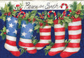 Front of a patriotic greeting card depicting five holiday stockings (two American flag, three red striped) adorned with holly, berries, and candy canes, above the text 'Peace on Earth' on a blue background.