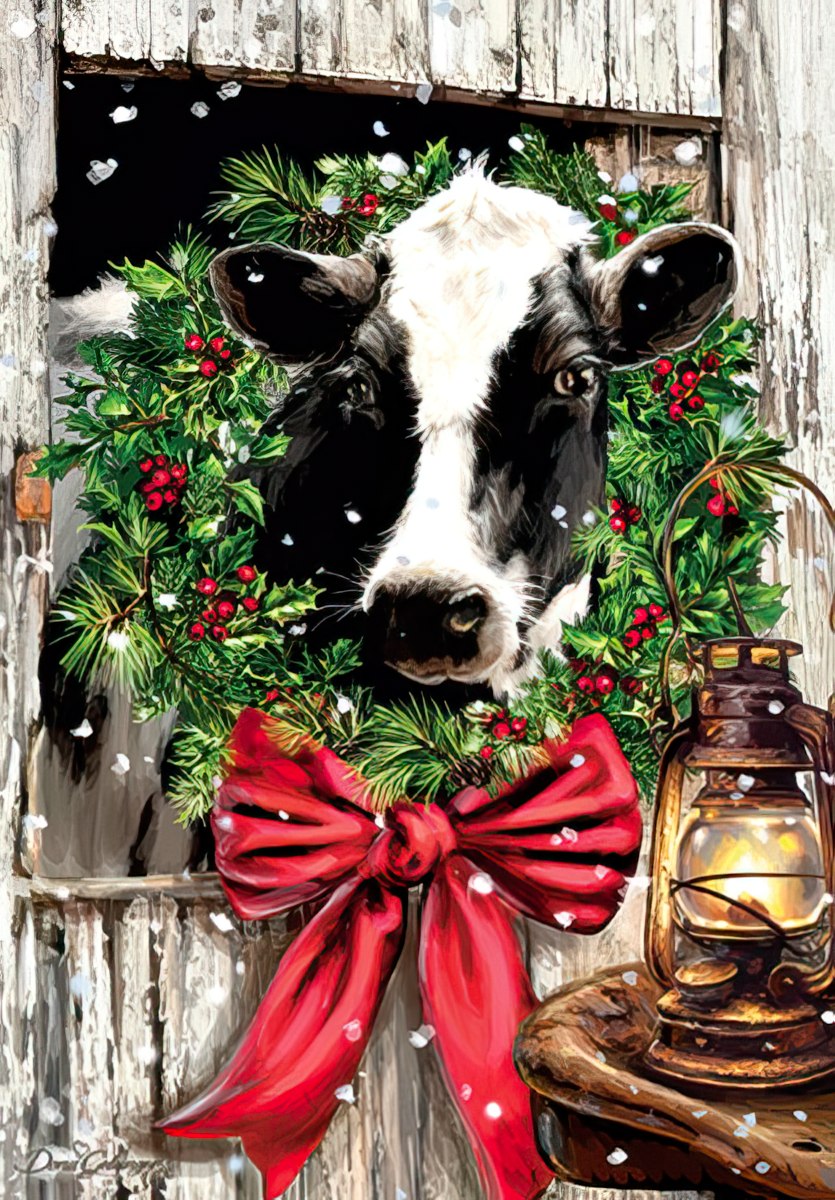 holstein cow with wreath around its neck in barn stall