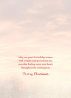 Inside of a holiday greeting card with a heartfelt message wishing wonder, good cheer, and warmth for the coming year, against a soft sky background.