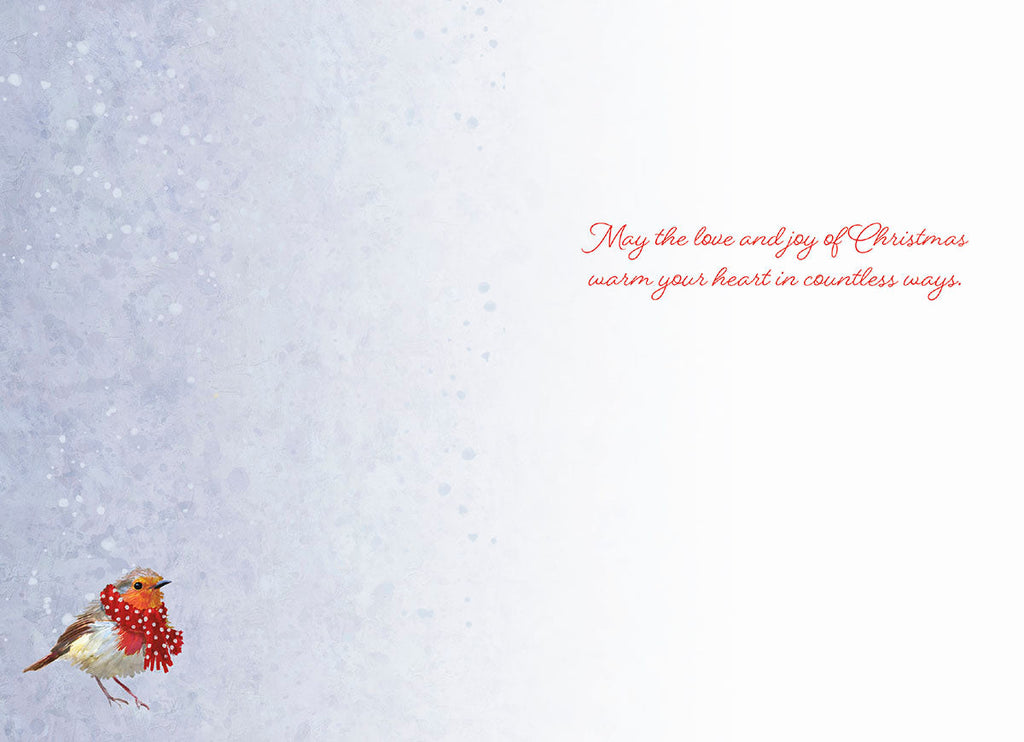 Inside of a holiday greeting card with a small robin bird in a red scarf at the bottom left, against a subtle snowy textured light blue background. Features the heartfelt message 'May the love and joy of Christmas warm your heart in countless ways.' on the right.