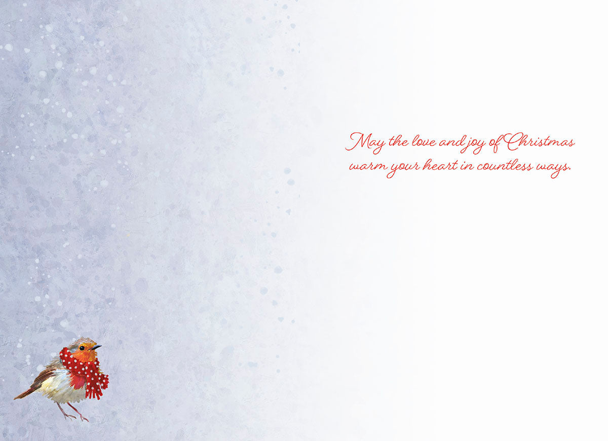 Inside of a holiday greeting card with a small robin bird in a red scarf at the bottom left, against a subtle snowy textured light blue background. Features the heartfelt message 'May the love and joy of Christmas warm your heart in countless ways.' on the right.