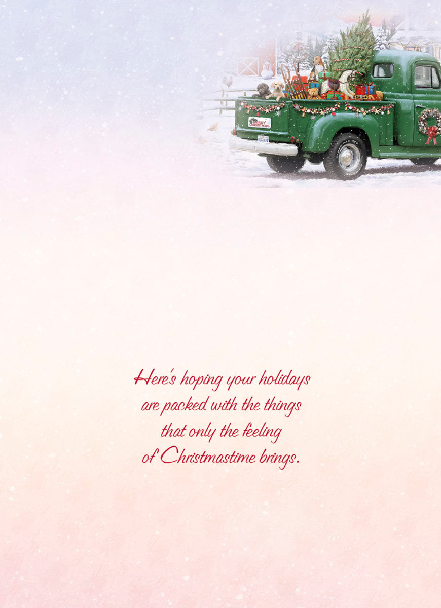 Interior of a holiday greeting card with elegant red script reading 'Here's hoping your holidays are packed with the things that only the feeling of Christmastime brings.' against a soft, snowy background with a subtle festive truck in the distance.