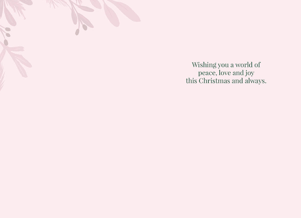 Inside of a religious Christmas greeting card with a pale pink background and subtle light pink foliage in the corner. Black text reads 'Wishing you a world of peace, love and joy this Christmas and always.'