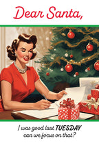 Retro style greeting card featuring a woman in a red dress writing a letter to Santa beside a decorated tree and gifts, with the text 'Dear Santa, I was good last TUESDAY can we focus on that?'