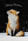 Front of a festive holiday greeting card featuring a contented red fox sitting in fresh snow with eyes closed, enjoying falling snowflakes against a dark, wintry background, with 'Merry Christmas' text.