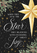 Front of a religious holiday greeting card featuring a radiant golden star against a dark, starry night sky with watercolor holly and berries. Elegant white script reads 'When they saw the Star they rejoiced with exceeding great Joy'.