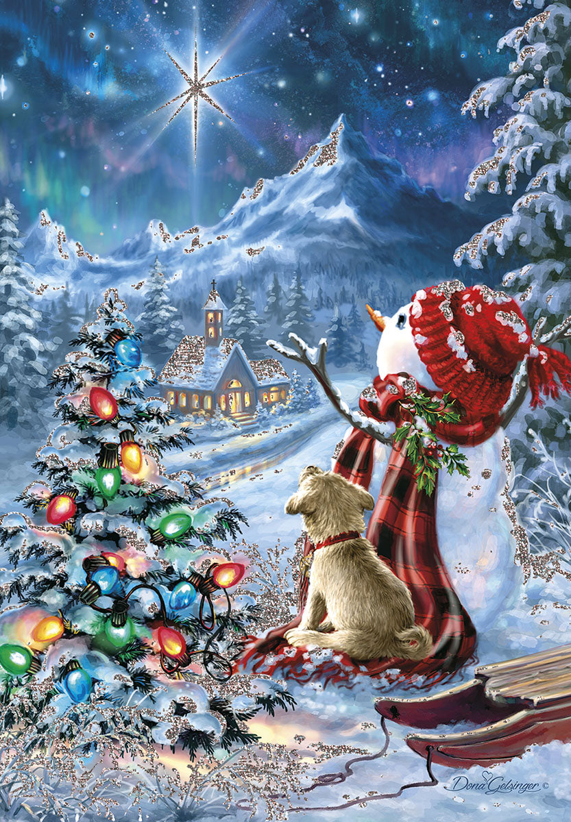 Front of a religious Christmas greeting card featuring a snowy winter wonderland. A large, bright guiding star shines over snow-capped mountains and a cozy, illuminated church. In the foreground, a friendly snowman in a red plaid scarf stands beside a cute dog and a festive evergreen tree with colorful lights, all sparkling with glittery snow.