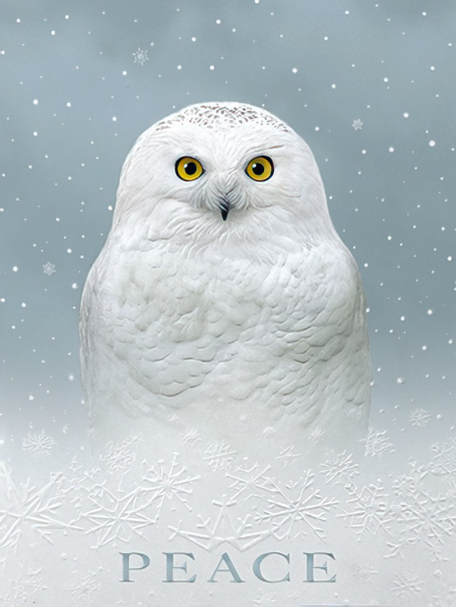Front of a peaceful winter holiday greeting card featuring a majestic white snowy owl with bright yellow eyes amidst falling snow and embossed snowflakes, with the word 'PEACE' prominently displayed at the bottom, conveying serene season's greetings.
