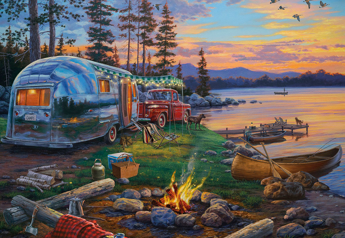 Panoramic view of a vintage silver camper and red truck by a lake at sunset, with a campfire and canoe on Father's Day.