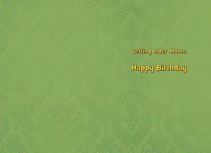 Inside of a funny birthday card with a green patterned background and yellow text 'Getting older blows. Happy Birthday'.