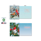 Two open greeting cards demonstrating front and inside designs. One card features a snowy house with cardinals on a pine branch, with an inside message 'Wishing you quiet moments... Season's Greetings'. The second card shows a cardinal on a decorated Christmas tree, with an inside message 'May your holidays be decorated with one little joy after another!'. Labels indicate 'Sustainably-Sourced Paper', 'Soy-Based Inks', and 'Made In USA', and card dimensions 5"x7".