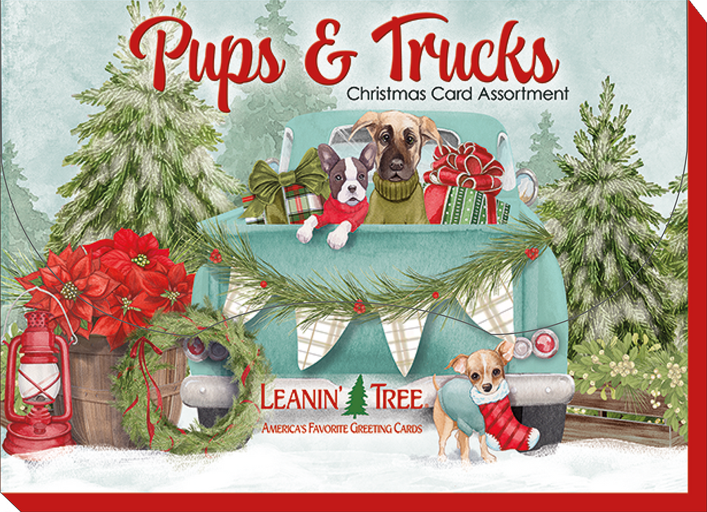 Leanin' Tree Pups & Trucks Christmas Card Assortment box cover with two dogs in a light blue vintage pickup truck adorned with holiday garland and presents, surrounded by snowy evergreens.