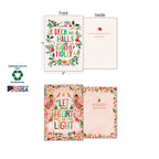 Two holiday greeting cards, 'Deck the Halls' and 'Let Your Heart Be Light', shown with front and inside messages, highlighting sustainable paper, soy inks, and Made in USA.