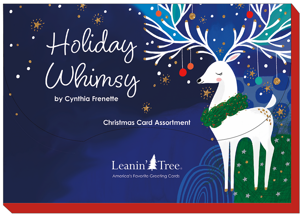 Close-up of the 'Holiday Whimsy by Cynthia Frenette' Christmas Card Assortment box lid from Leanin' Tree, featuring a white reindeer with decorated antlers on a deep blue background with golden stars.