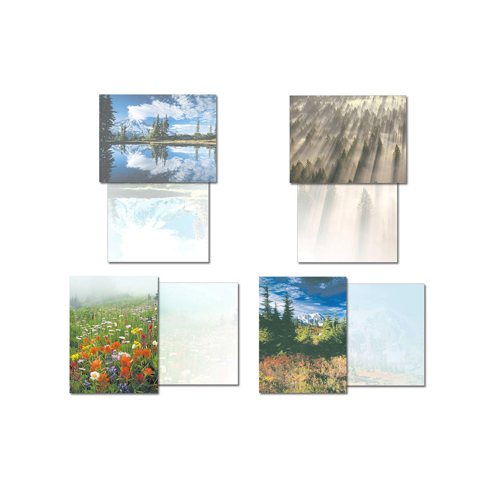 Four Pacific Northwest nature greeting cards displayed open, revealing their blank interiors. Designs include a mountain reflecting in a lake, sun rays through a forest, a field of wildflowers, and autumn trees.