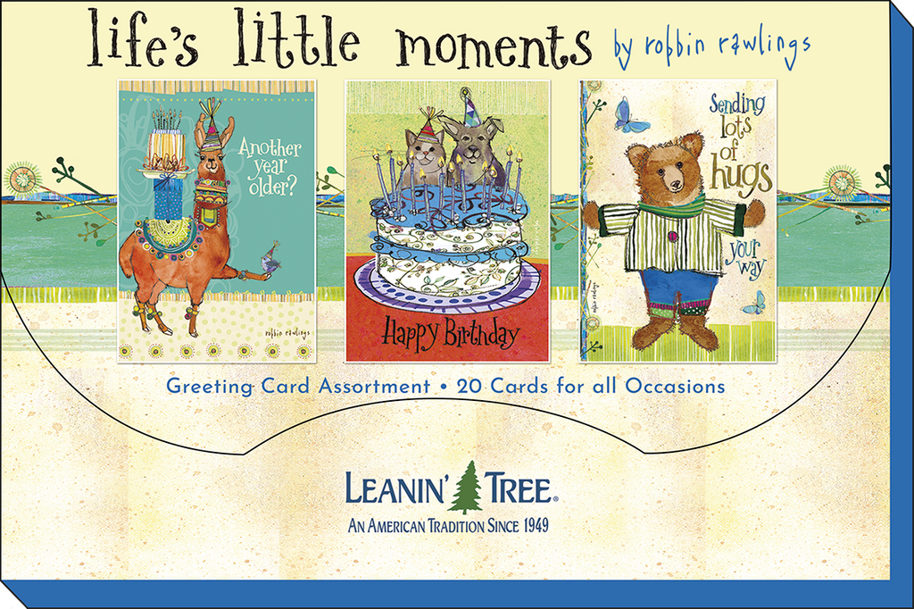 Packaging for 'Life's Little Moments' greeting card assortment, featuring three sample cards: a birthday llama, festive dogs/cats on a cake, and a bear sending hugs.