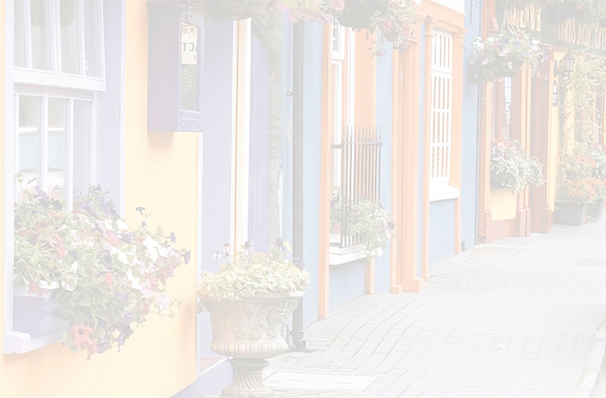 Faded, pastel view of a narrow European street with colorful houses in yellow, blue, and purple, with flower boxes.