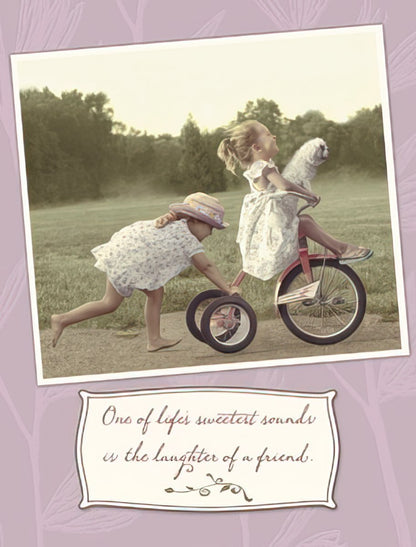 Two young girls playing outside, one on a tricycle and the other pushing, with a quote about the laughter of a friend.