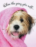 Front of an encouragement greeting card featuring a fluffy brown and white dog wrapped in a pink towel, sticking out its tongue, with black script text "When the going gets ruff...".