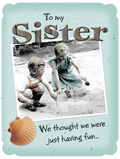 Heartfelt sister birthday card featuring vintage photo of two young girls playing in sand, nostalgic 'To my Sister' message, seashell accent.