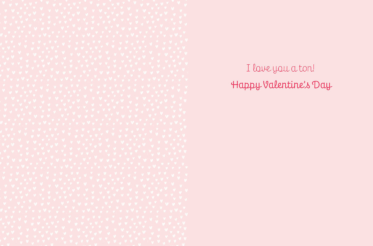Inside of a cute greeting card with a light pink heart pattern background and the message 'I love you a ton! Happy Valentine's Day' in pink script font.