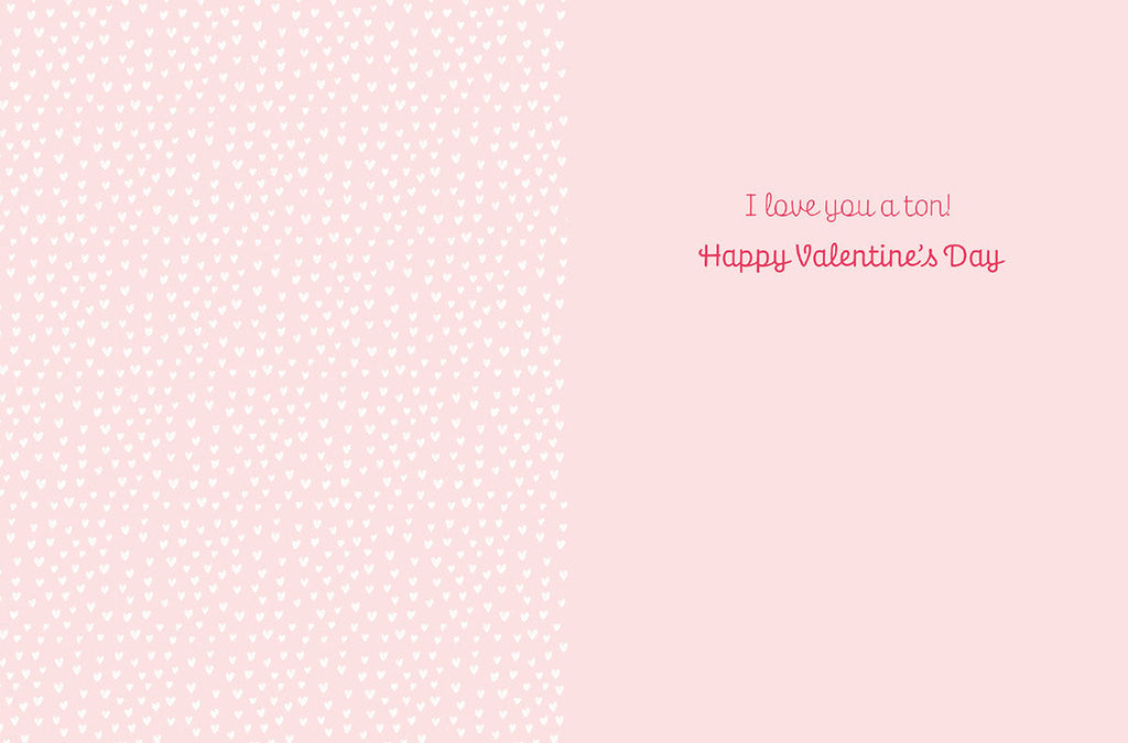 Inside of a cute greeting card with a light pink heart pattern background and the message 'I love you a ton! Happy Valentine's Day' in pink script font.