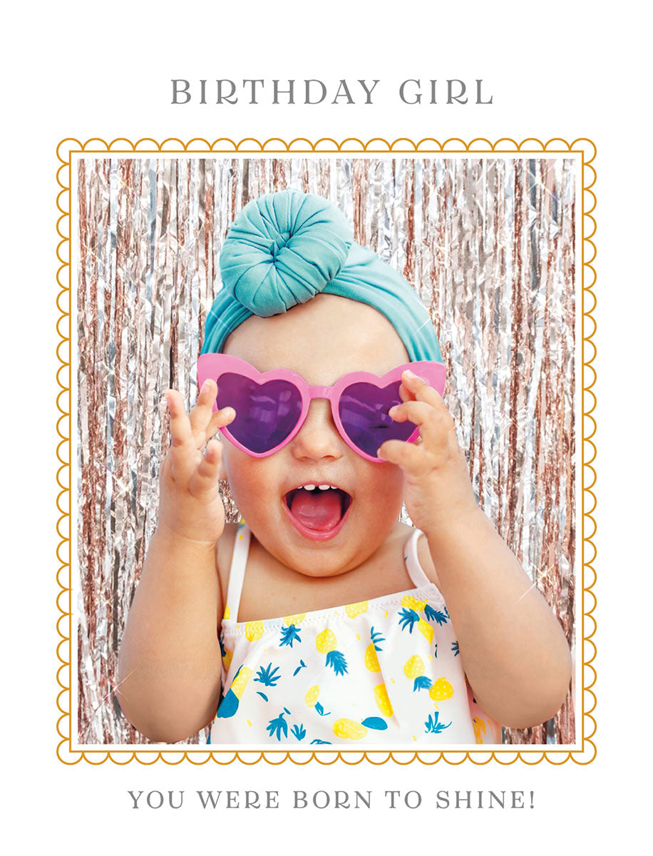 Front of a cute birthday greeting card for a girl, featuring an adorable baby wearing pink heart-shaped sunglasses and a pineapple print romper, with a teal headwrap, smiling brightly against a glittery background. Text reads 'Birthday Girl, You Were Born to Shine!'. Perfect for a little one's special day.