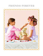 Adorable 'Friends Forever' greeting card featuring two happy young girls playing dress-up with makeup on a bed, alongside a teddy bear, framed by a whimsical border. Ideal for children's special moments.