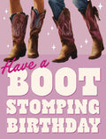 Front of a fun birthday greeting card featuring four pairs of cowboy boots dancing on a vibrant pink and purple background with sparkling stars. The text reads 'Have a BOOT STOMPING BIRTHDAY' in a playful Western-style font, perfect for a lively celebration.