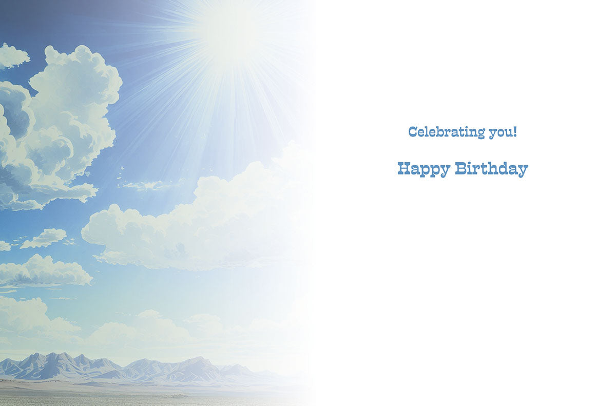 Inside view of a celebratory greeting card with 'Celebrating you! Happy Birthday' text on a white background, partially framed by a bright blue sky, sun, and clouds on the left.