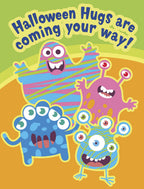 Front of a playful Halloween greeting card featuring four colorful, smiling cartoon monsters in blue, pink, and striped patterns, with text 'Halloween Hugs are coming your way!' against a vibrant green and orange background.