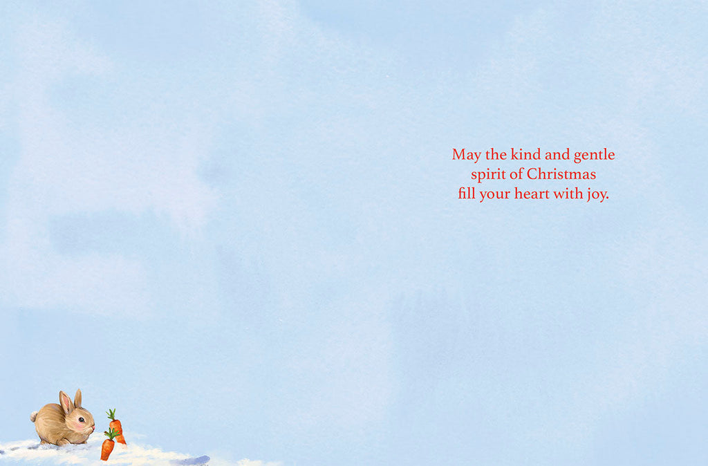 Inside of a holiday greeting card with a light blue background. A small bunny sits beside two carrots in the bottom left corner. Red script text reads: 'May the kind and gentle spirit of Christmas fill your heart with joy.'